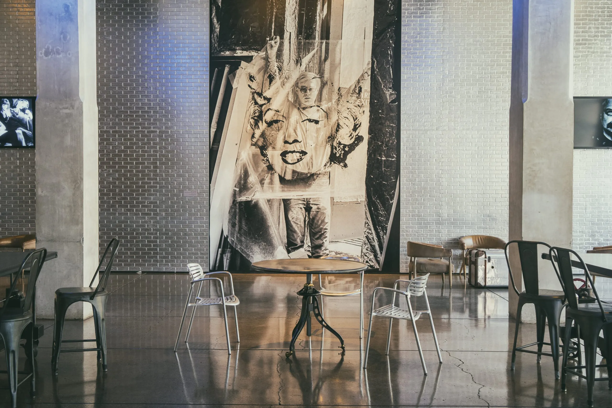 A towering black-and-white image of Andy Warhol over Marilyn Monroe anchors an empty cafe seating area in Pittsburgh.