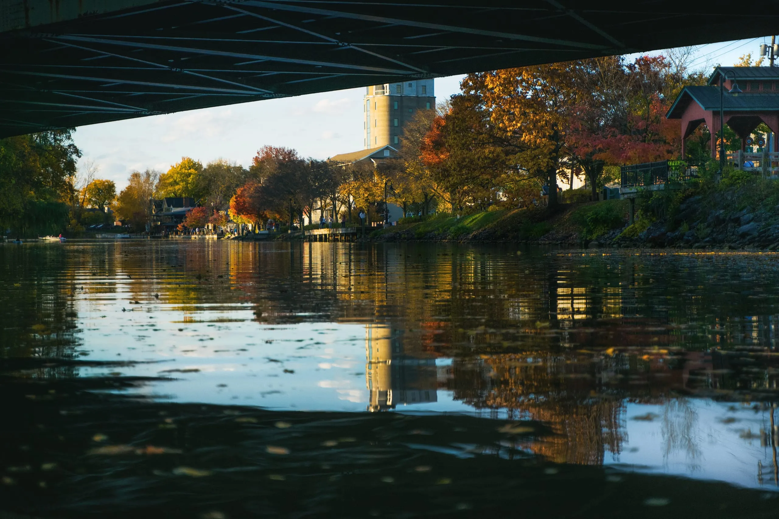 Autumn shoreline and bridge reflected in still Erie Canal water at blue hour