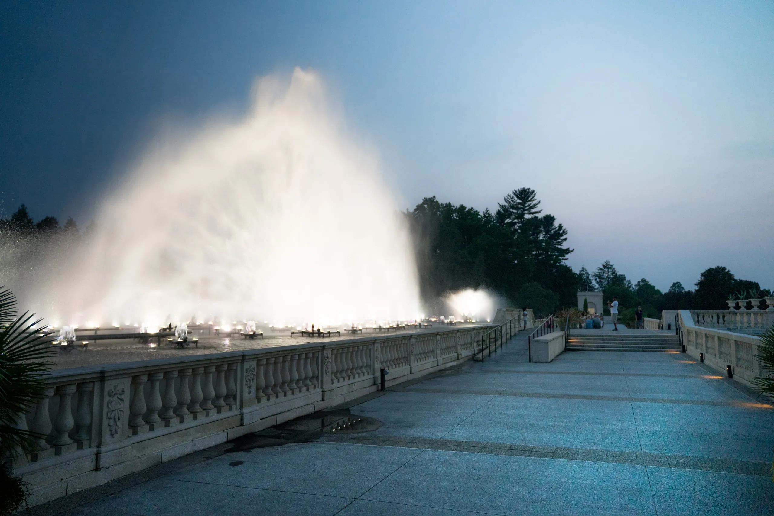 Illuminated fountain jets rising over a balustrade terrace at dusk, Longwood Gardens