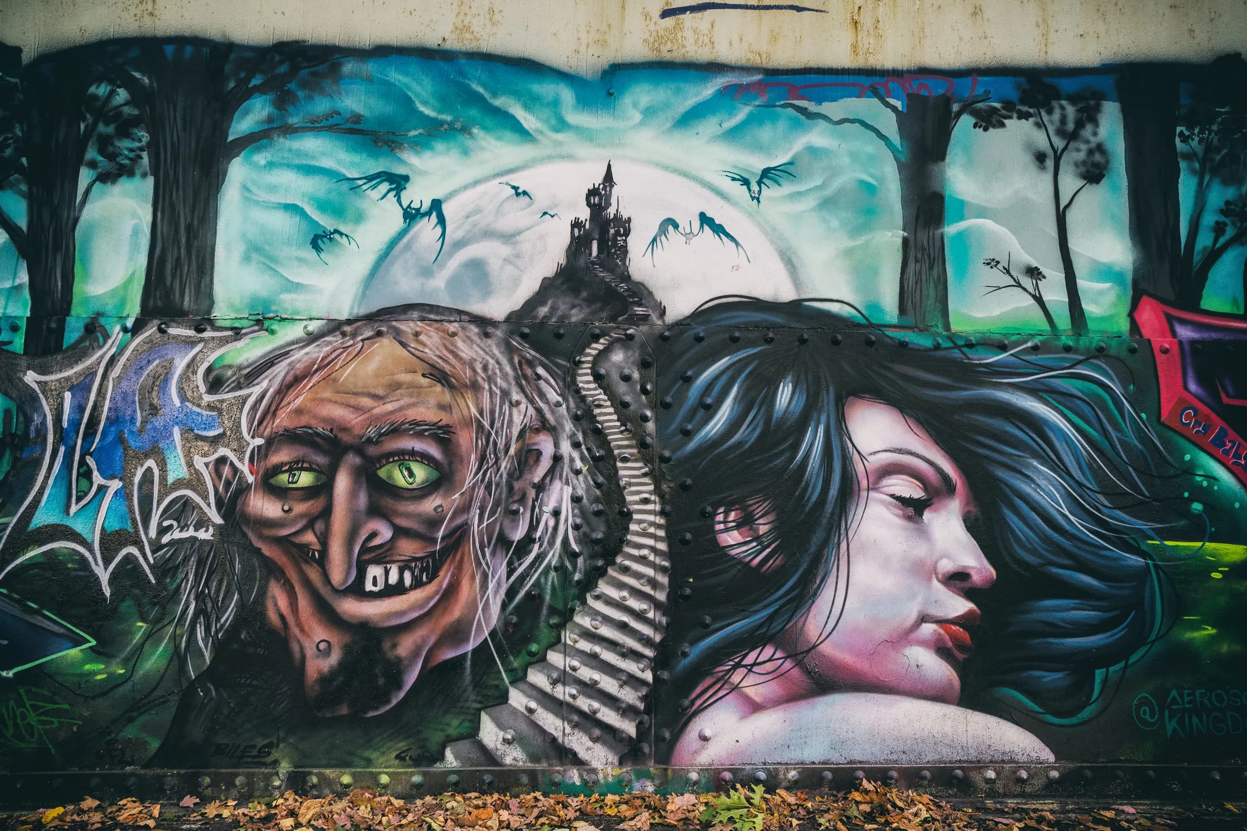 Painterly mural of a witch and a woman on a weathered industrial wall